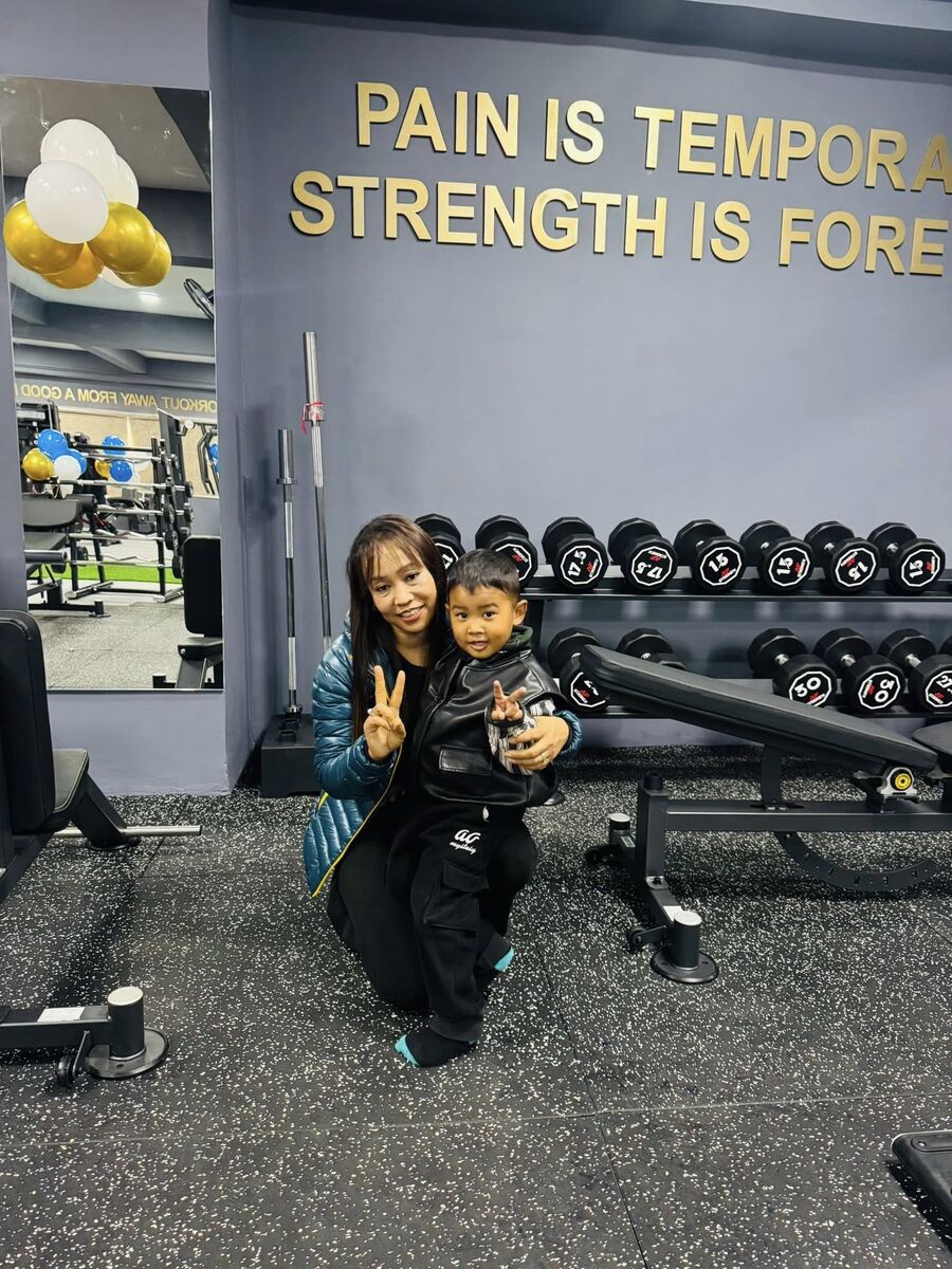 Wall slogan reading Pain is Temporary, Strength is Forever beside dumbbell racks
